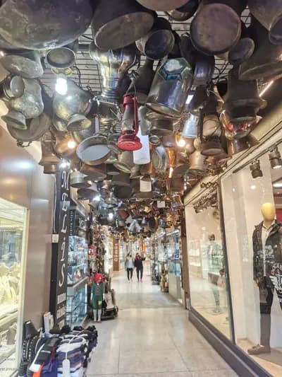 Gümüş ve antika dükkânlarının sıralandığı koridor; tavanda asılı bakır kaplar